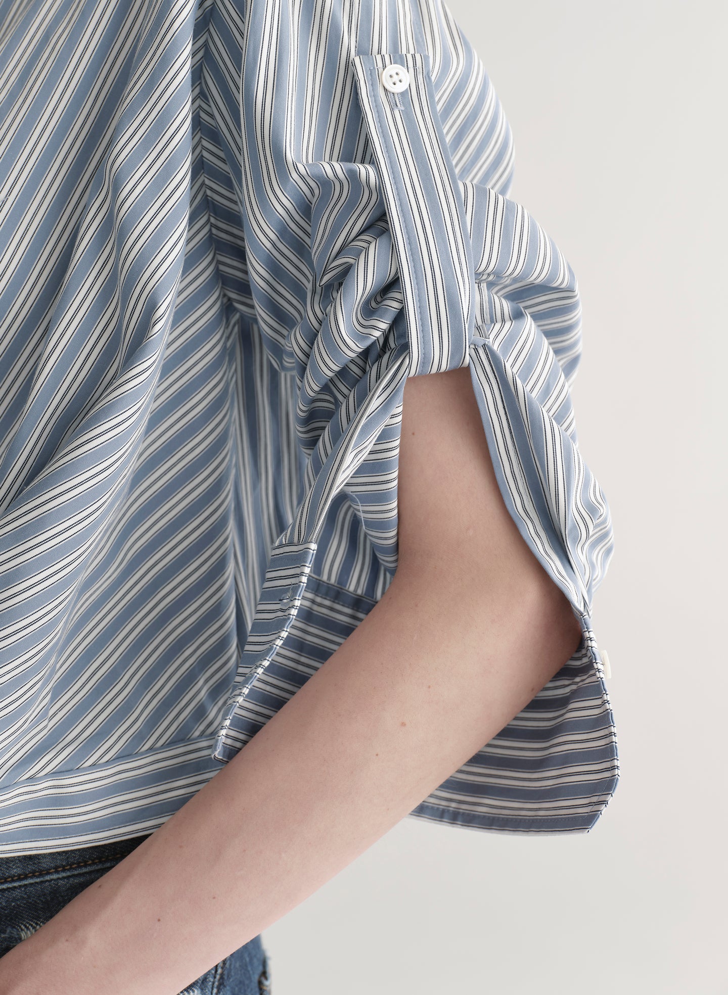 Woman wearing a striped shirt and jeans on a plain background
