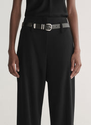 Person wearing a black sleeveless top and wide-leg pants on a white 