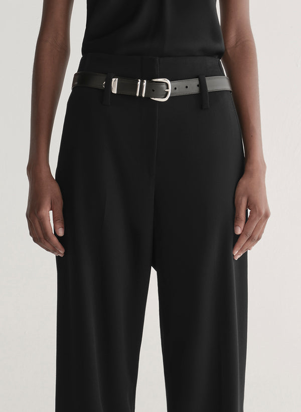 Person wearing a black sleeveless top and wide-leg pants on a white 