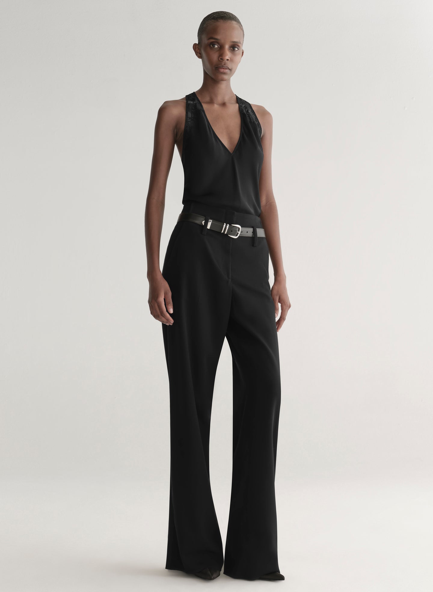 Person wearing a black sleeveless top and wide-leg pants on a white background