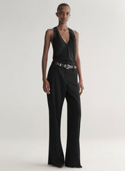 Person wearing a black sleeveless top and wide-leg pants on a white background