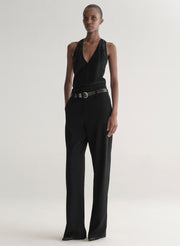 Person wearing a black sleeveless top and wide-leg pants on a white background