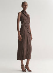 Woman wearing a brown striped top and matching midi skirt against a plain background