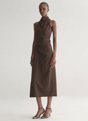 Woman wearing a brown striped top and matching midi skirt against a plain background