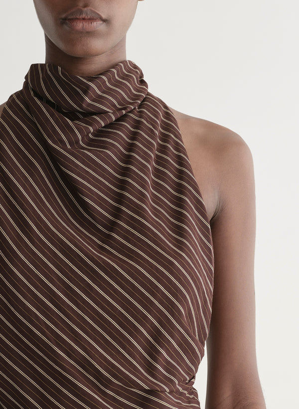 Woman wearing a brown striped top and matching midi skirt against a plain background