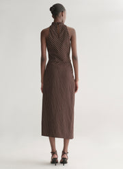 Woman wearing a brown striped top and matching midi skirt against a plain background