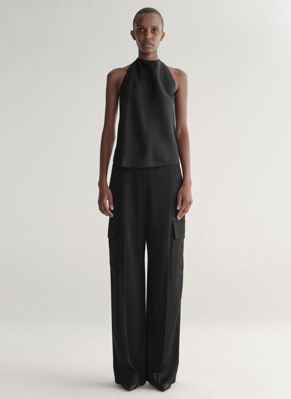 Person wearing a black sleeveless top and wide-leg pants on a light background