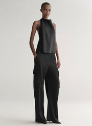 Person wearing a black sleeveless top and wide-leg pants on a light gray background