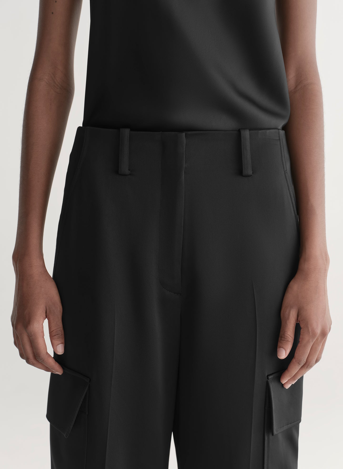 Person wearing black pants with a plain background