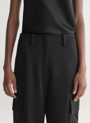 Person wearing black pants with a plain background