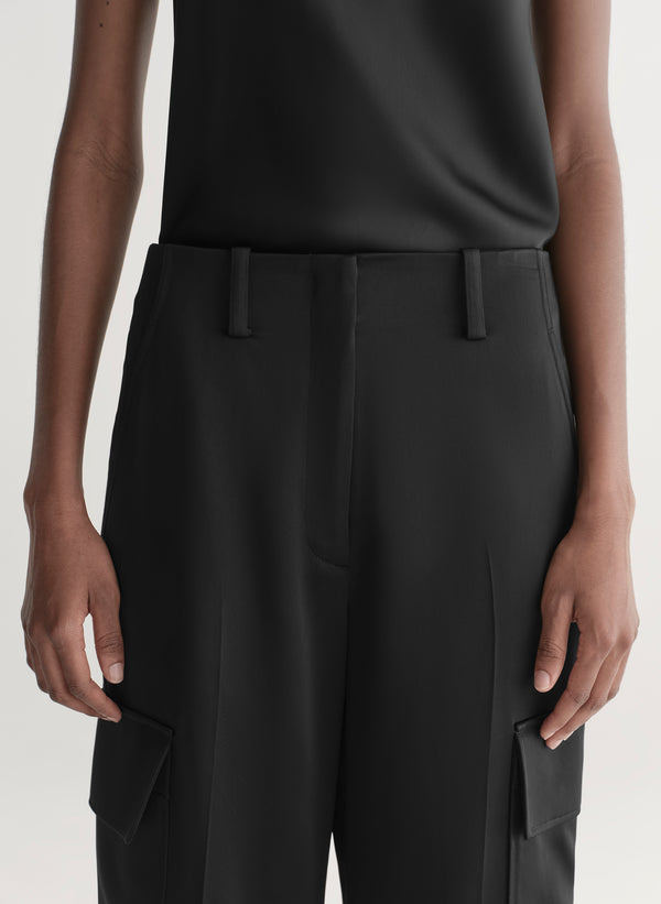 Person wearing black pants with a plain background