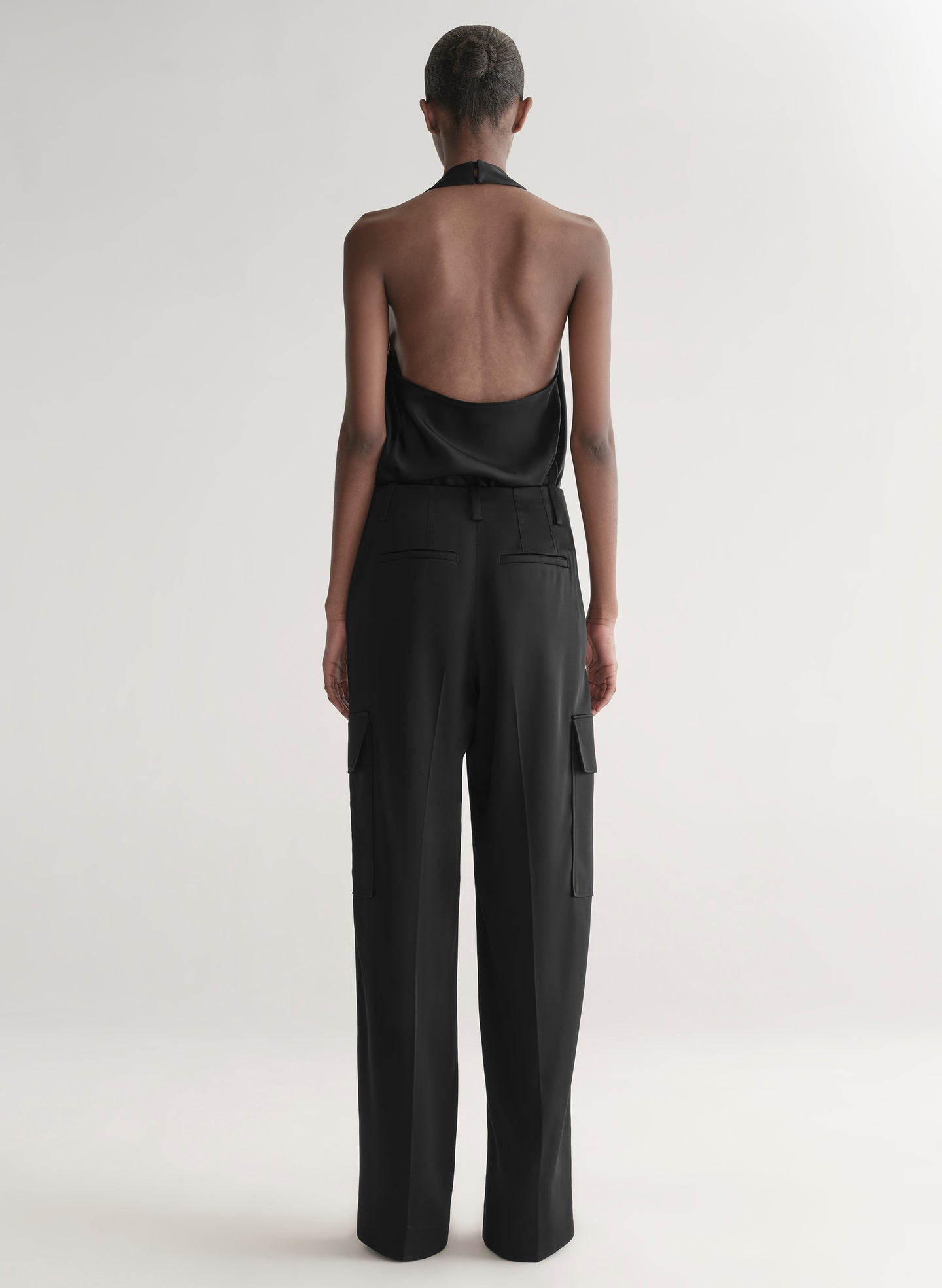 Person wearing a black outfit with open back on a white background