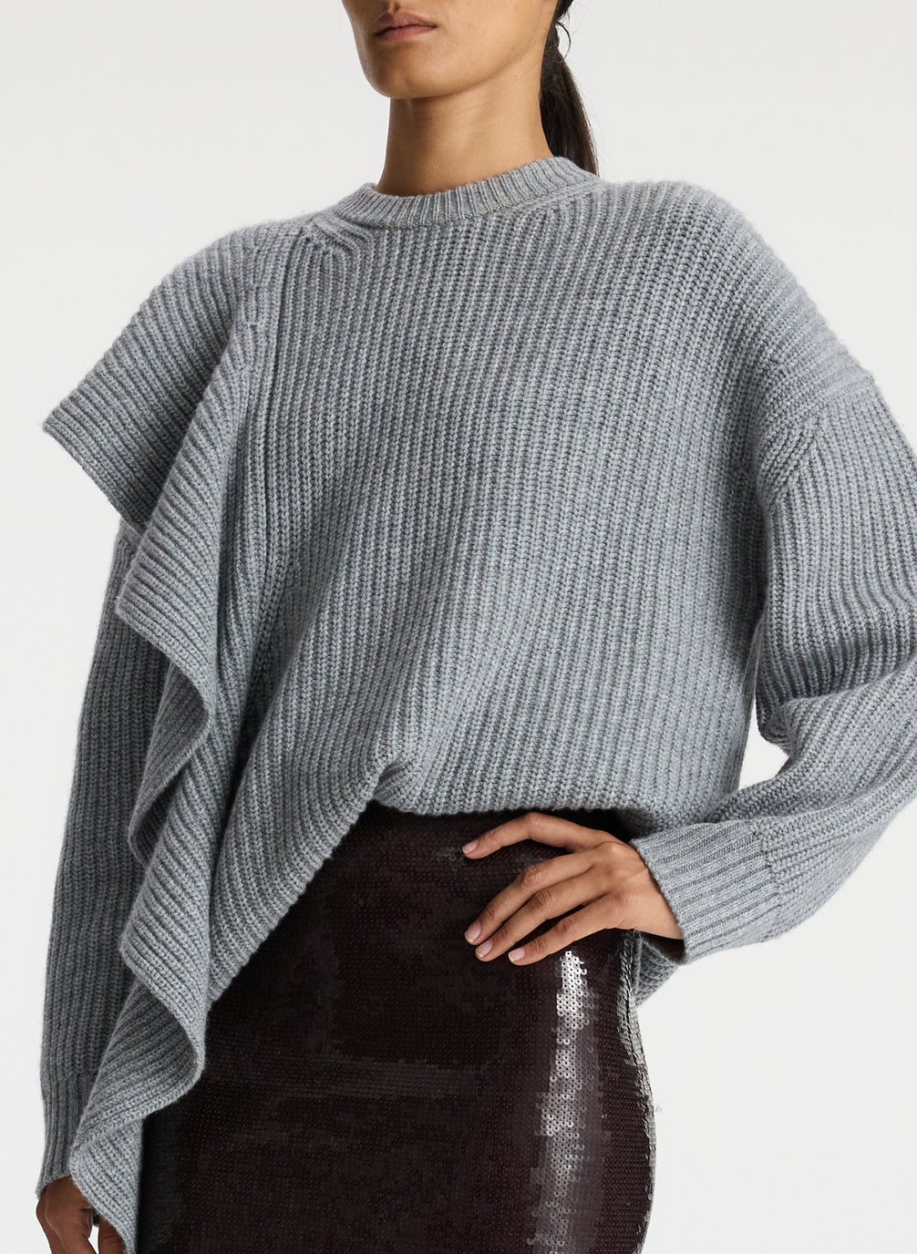 detail view of woman wearing grey sweater with ruffle and brown sequin midi skirt