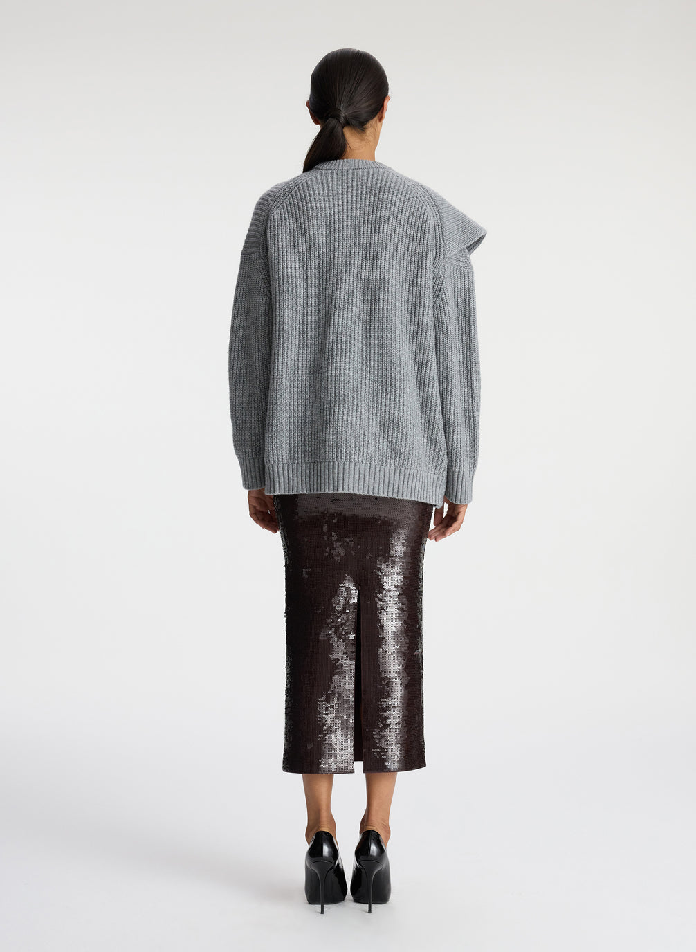 back view of woman wearing grey sweater with ruffle and brown sequin midi skirt