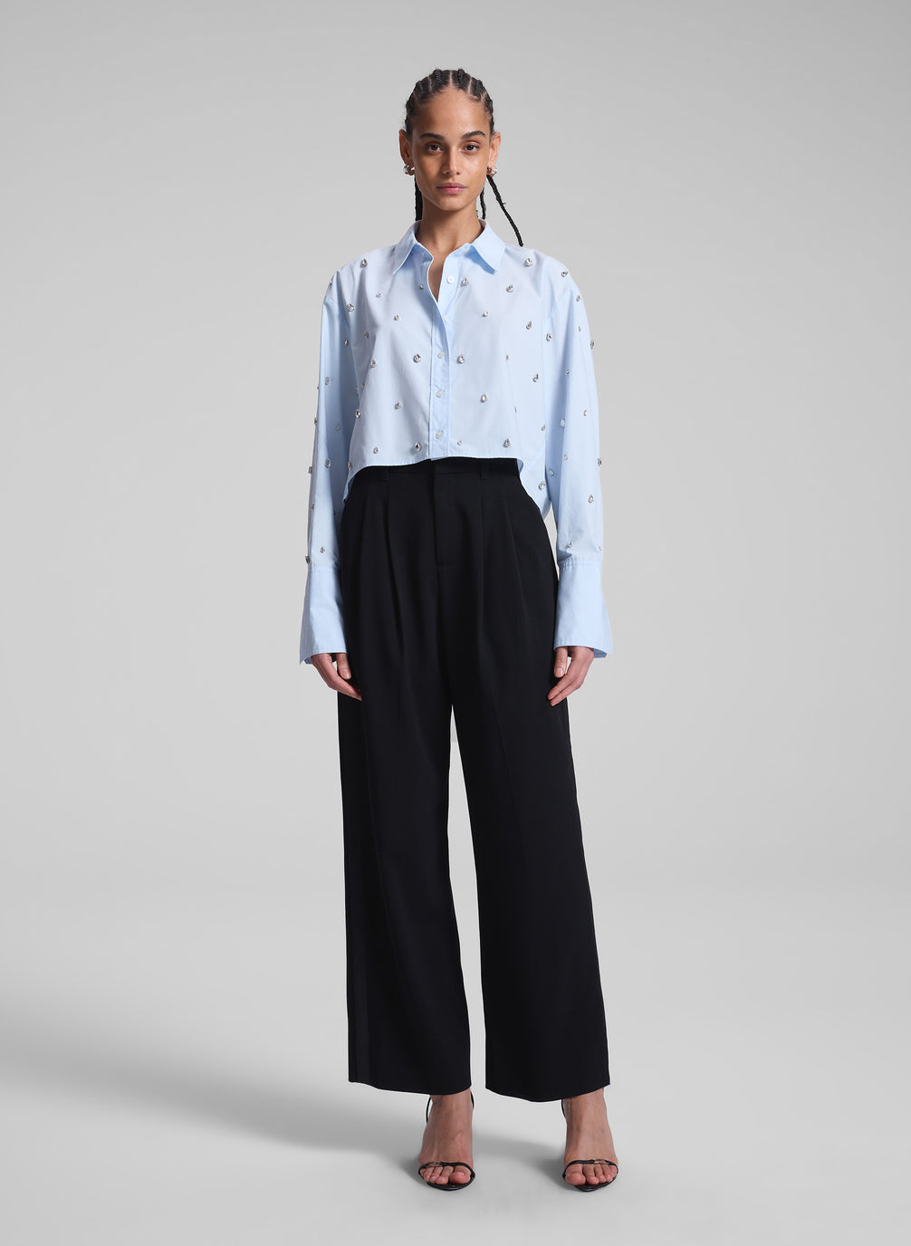 woman wearing light blue embellished shirt and black pants