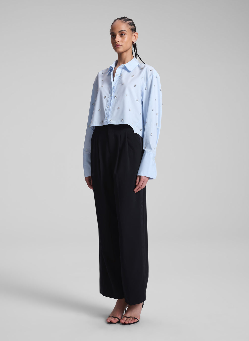 woman wearing light blue embellished shirt and black pants