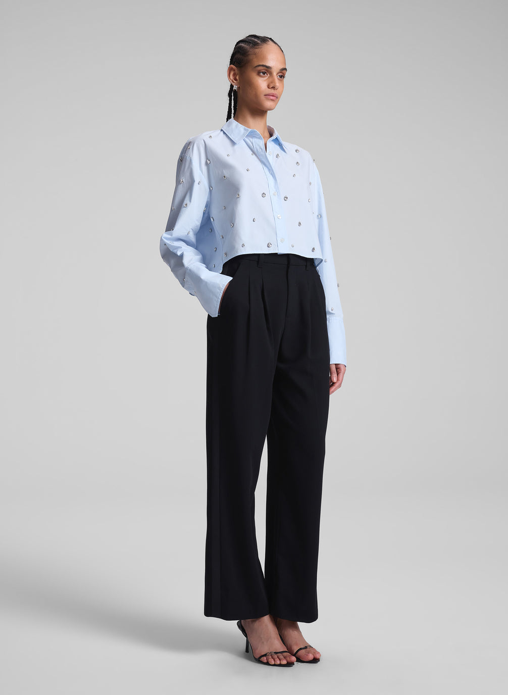 woman wearing light blue embellished shirt and black pants