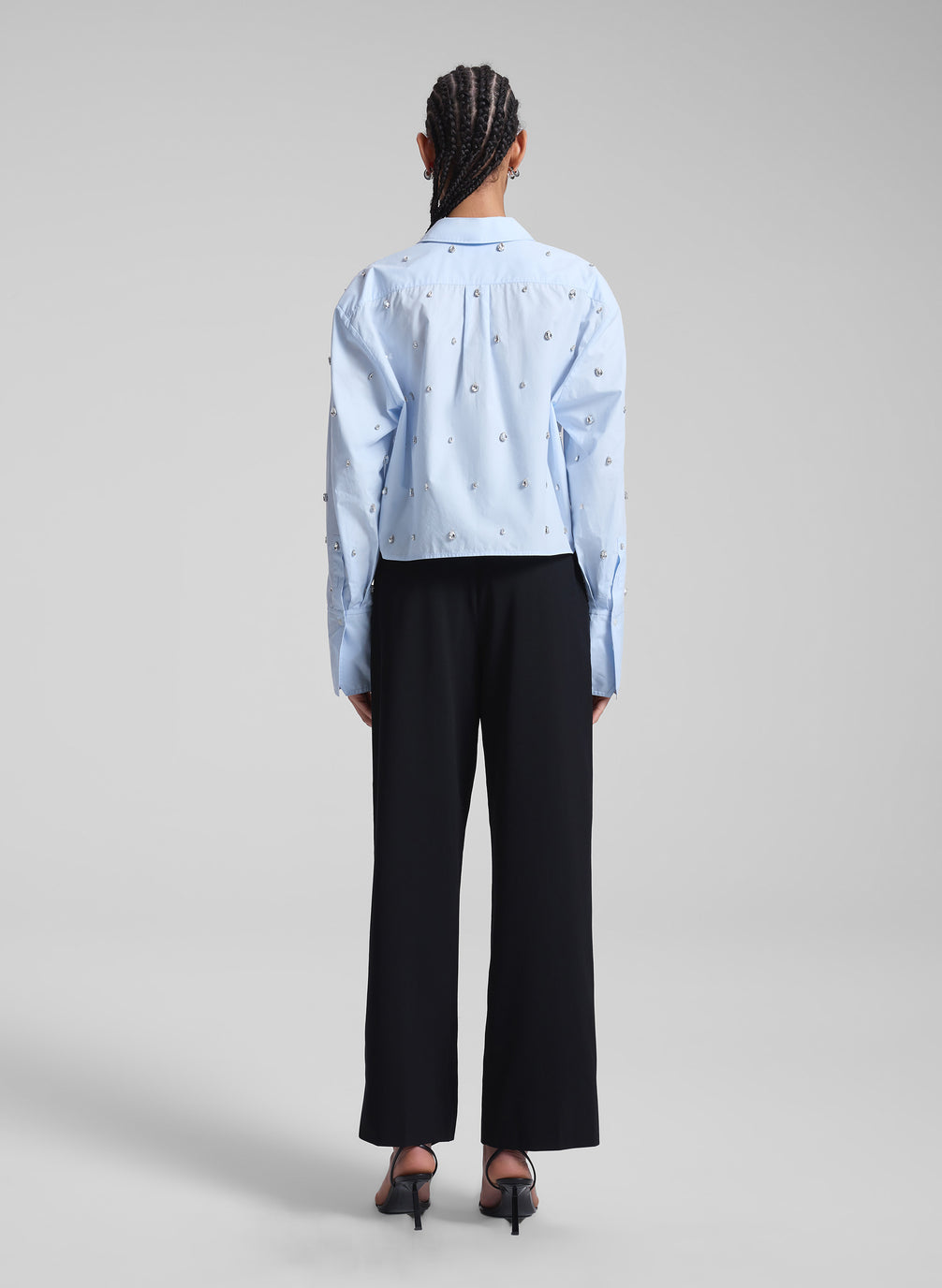 woman wearing light blue embellished shirt and black pants