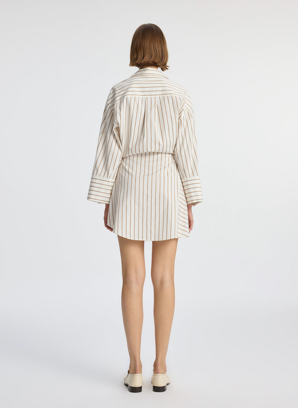 back view of woman wearing cream and brown striped wrapped shirtdress