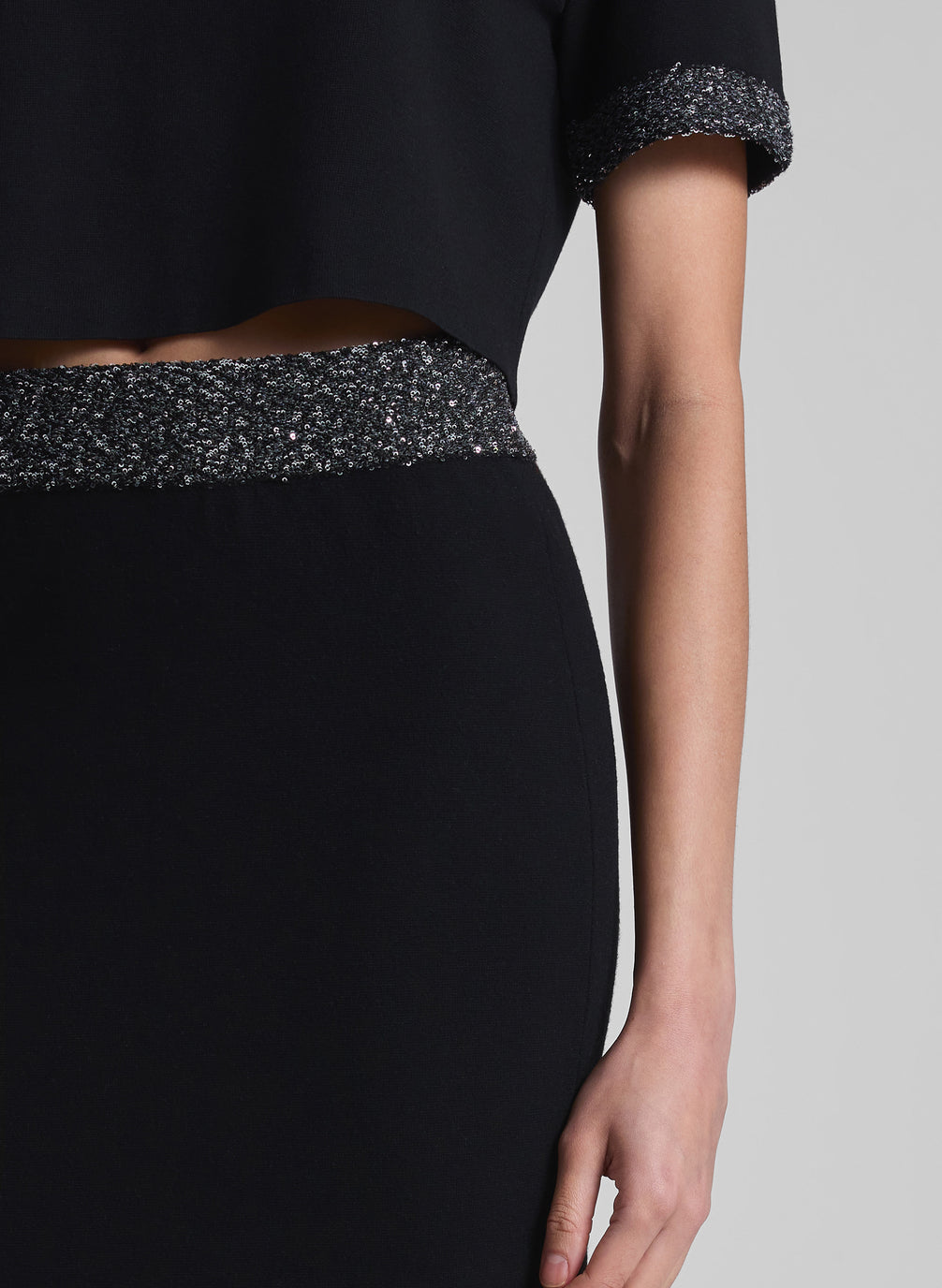 woman wearing black sequin trimmed top and matching skirt