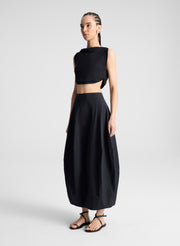 woman wearing black cropped tank and black midi skirt