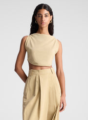 woman wearing tan cropped tank and beige draped pants