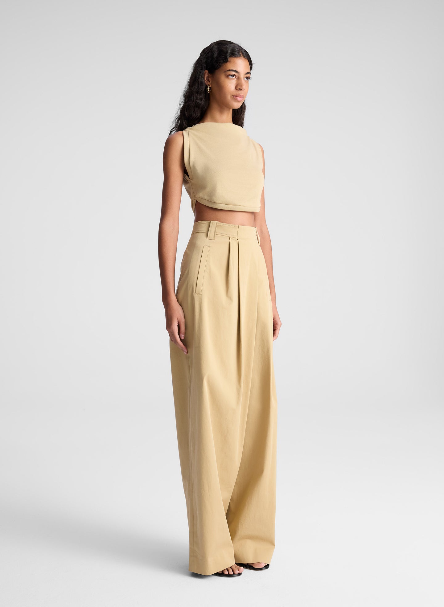 woman wearing tan cropped tank and beige draped pants