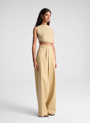 woman wearing tan cropped tank and beige draped pants