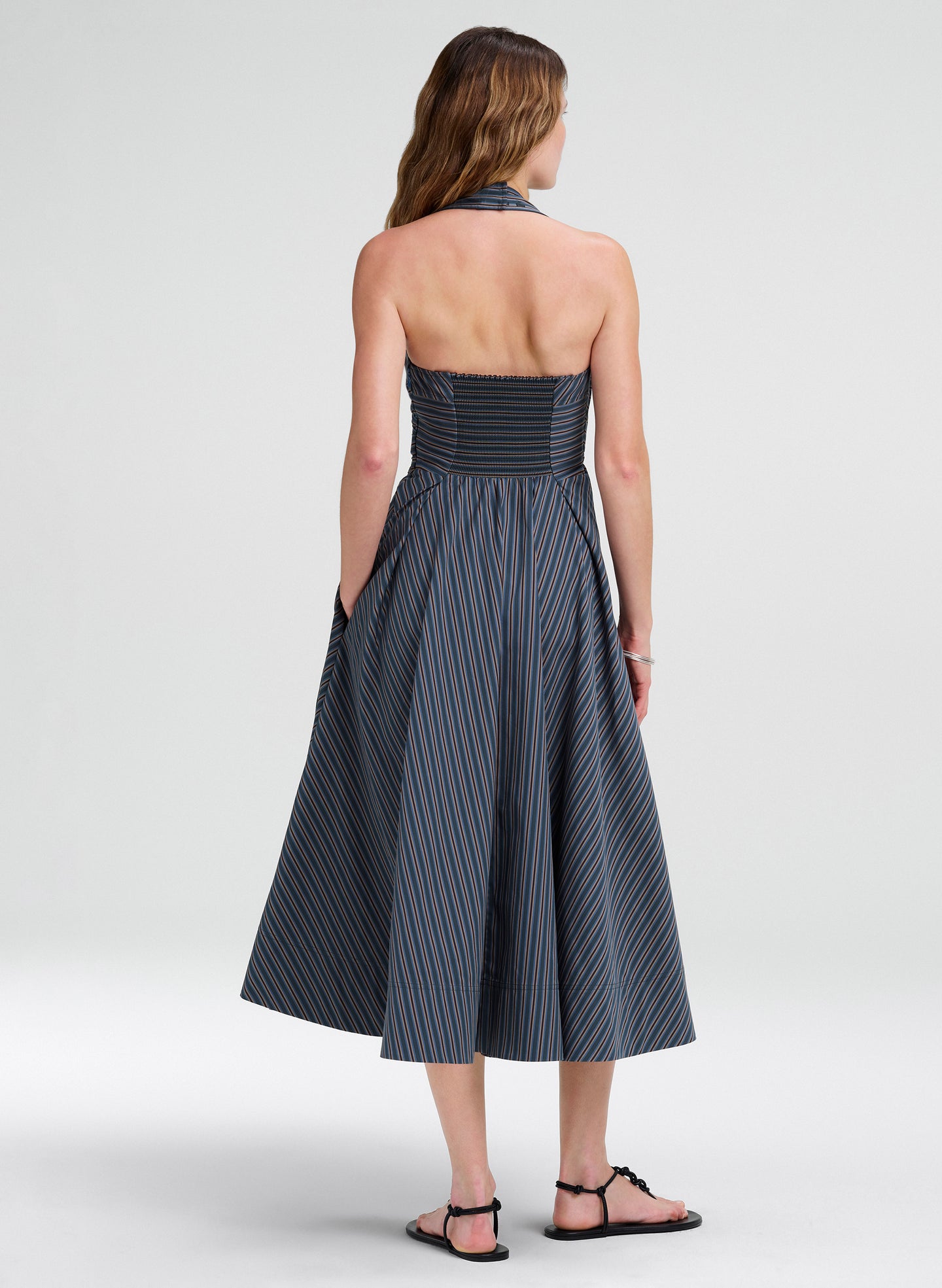 Woman wearing a halter midi striped dress on a white background
