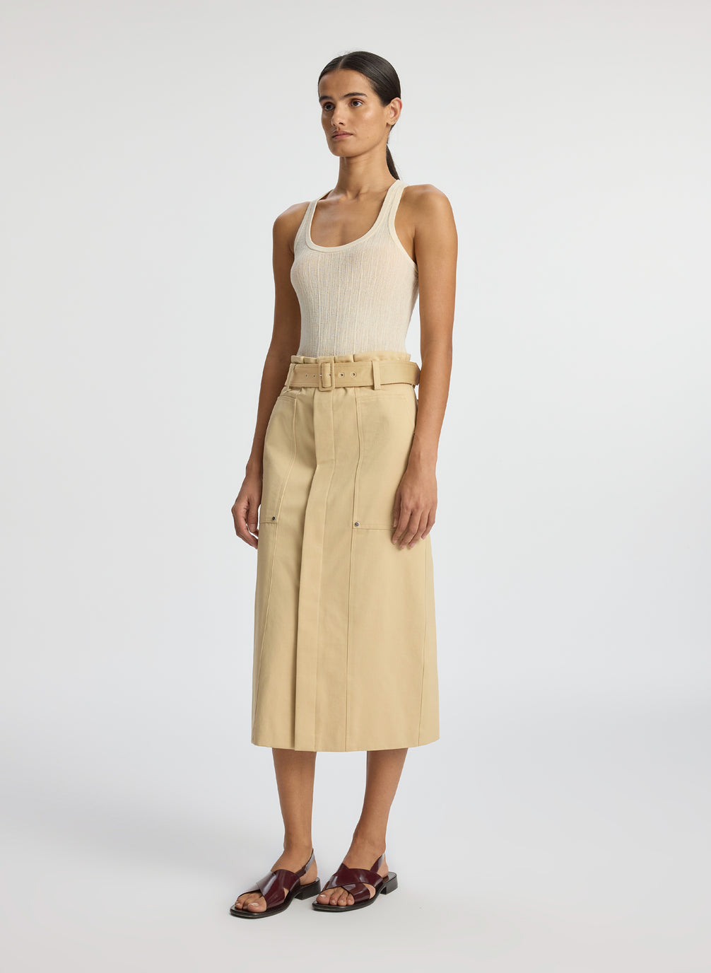 side view of woman wearing beige tank top and tan midi skirt