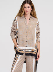 Woman wearing a patterned shirt and pants on a plain background