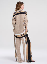 Woman wearing a patterned outfit with wide-leg pants on a white background