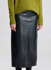 Woman wearing a green sweater and dark green leather skirt on a white background
