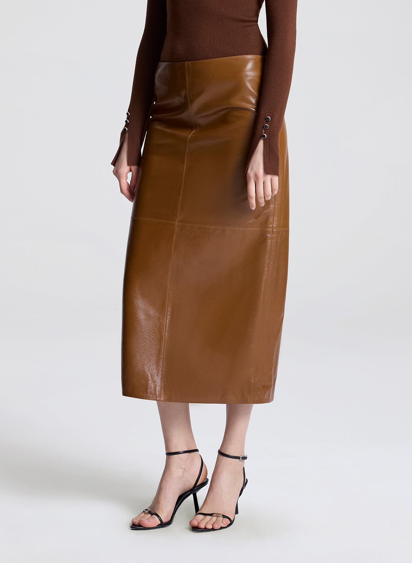 Brown leather skirt worn by a person on a white background
