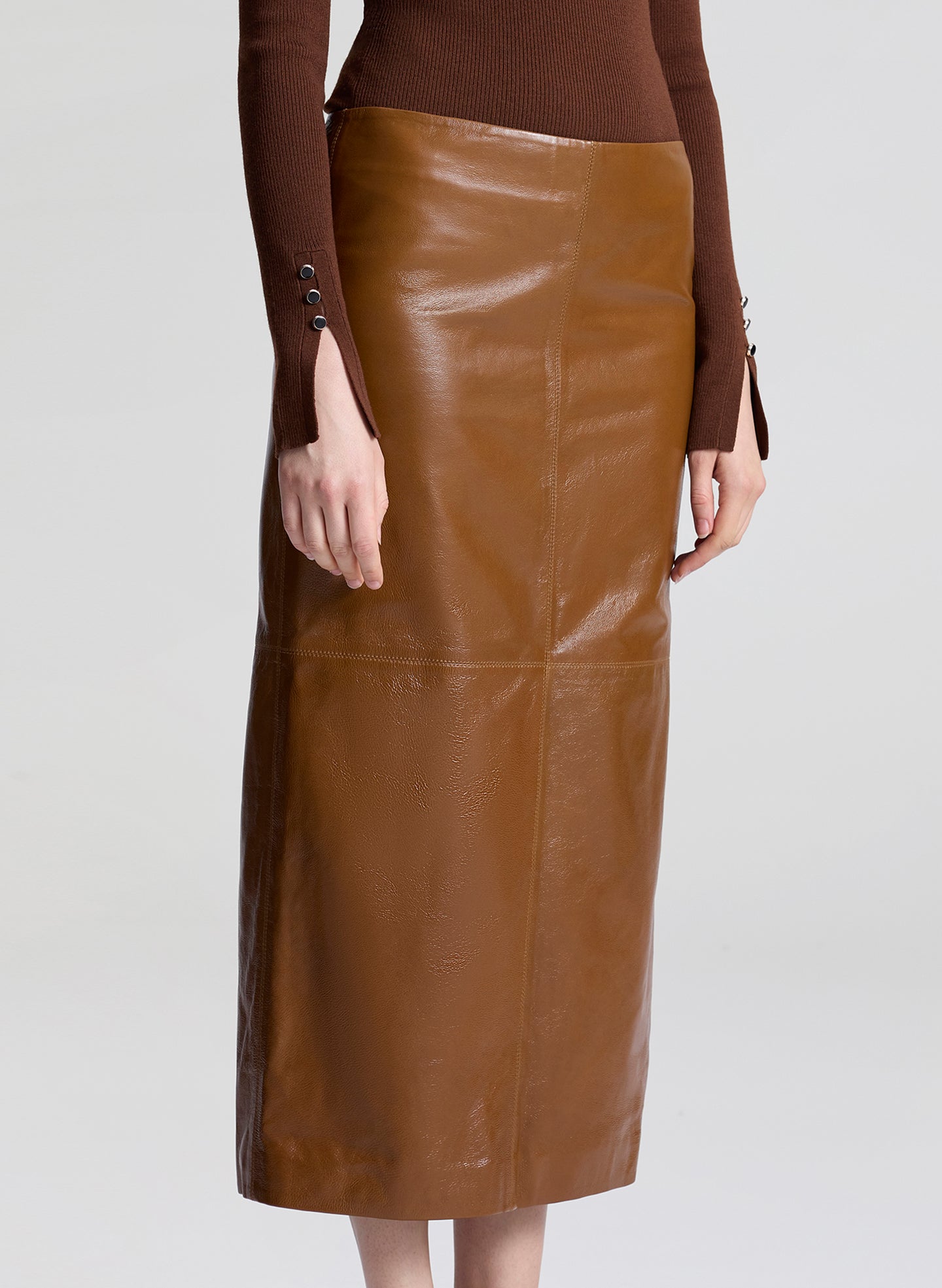 Brown leather skirt worn by a person on a light gray background