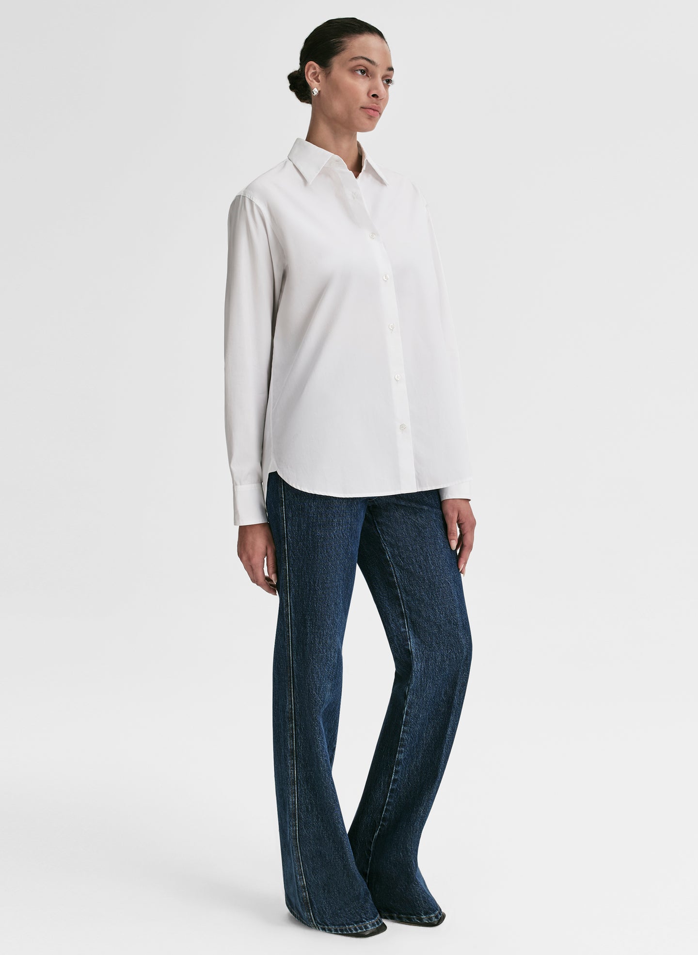 Woman wearing a white shirt and dark blue jeans on a white background