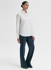 Woman wearing a white shirt and dark blue jeans on a white background