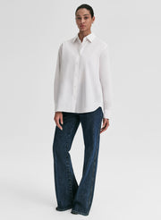 Woman wearing a white shirt and blue jeans on a light gray background