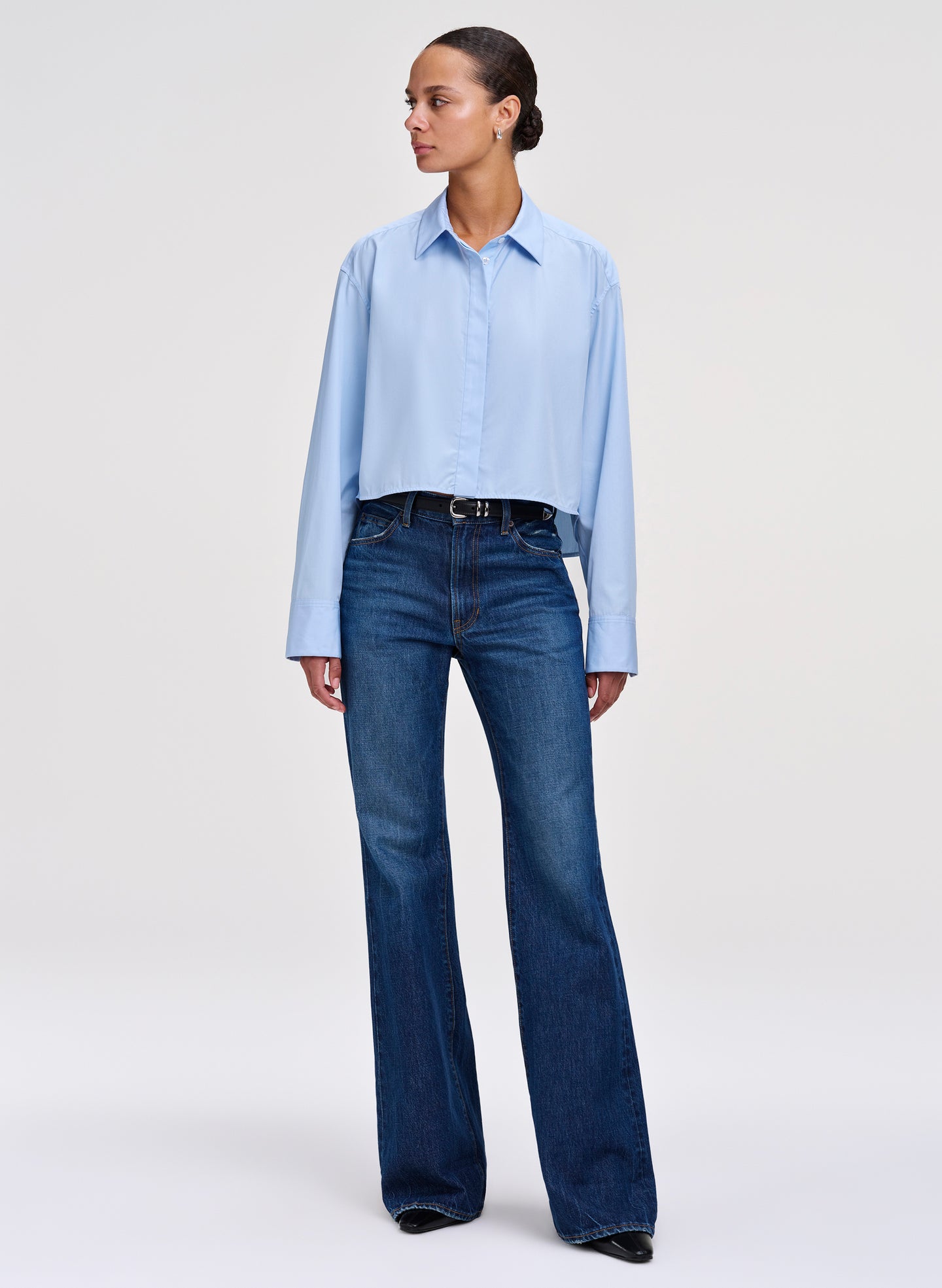 Person wearing a light blue shirt and dark blue jeans on a white background