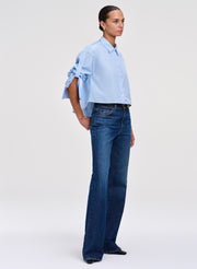 Woman wearing a light blue shirt and dark blue jeans on a white background