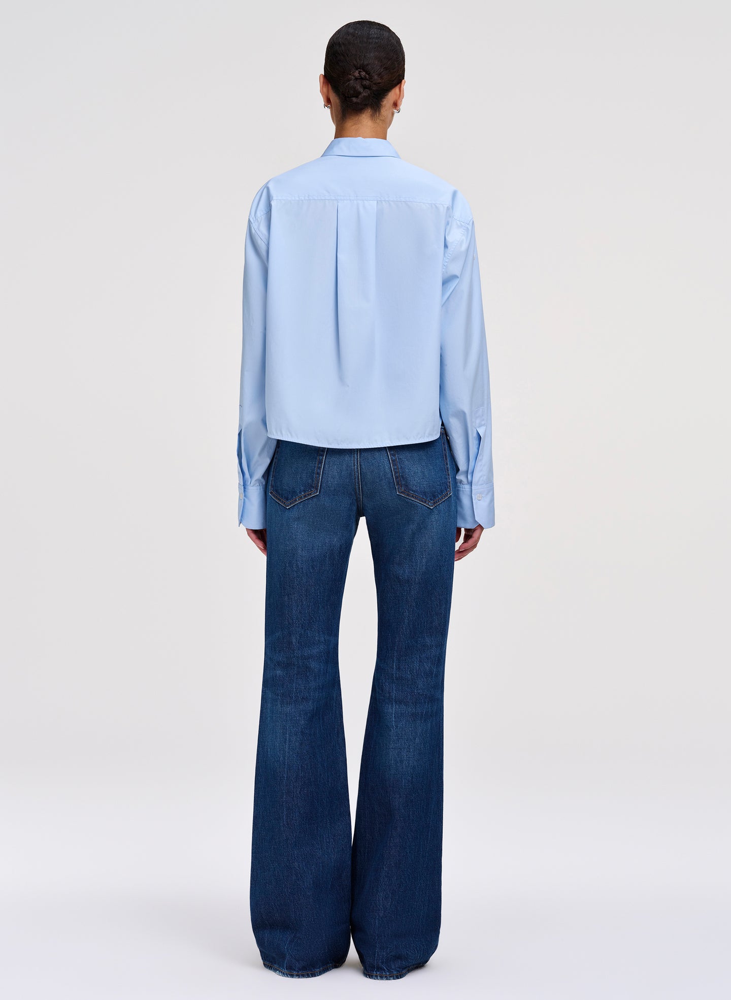 Person wearing a light blue shirt and dark blue jeans on a white background