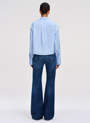 Person wearing a light blue shirt and dark blue jeans on a white background