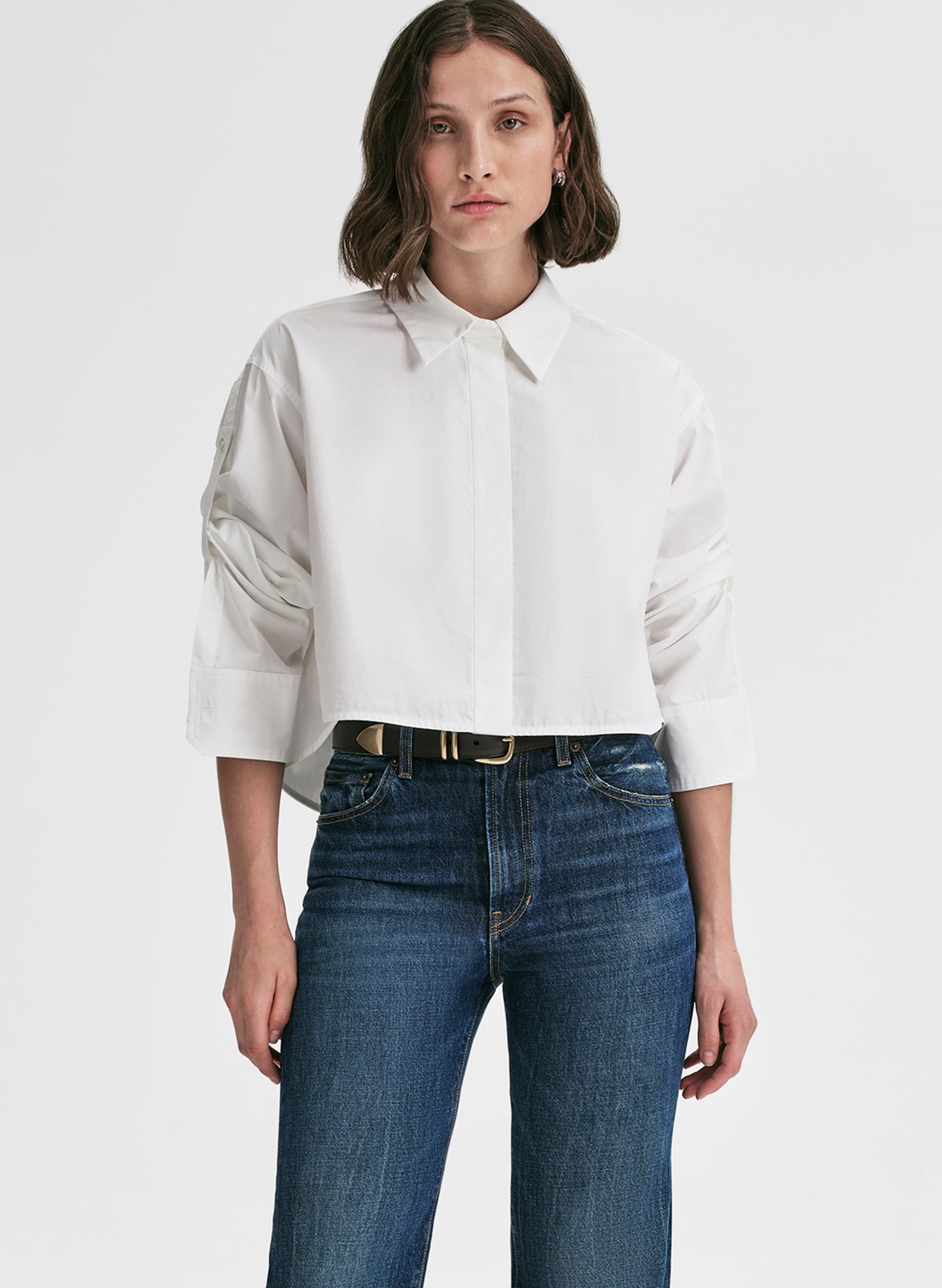 Woman wearing a white shirt and blue jeans on a plain background