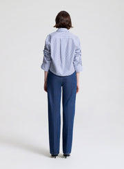 Person wearing a striped shirt and blue jeans on a light gray background