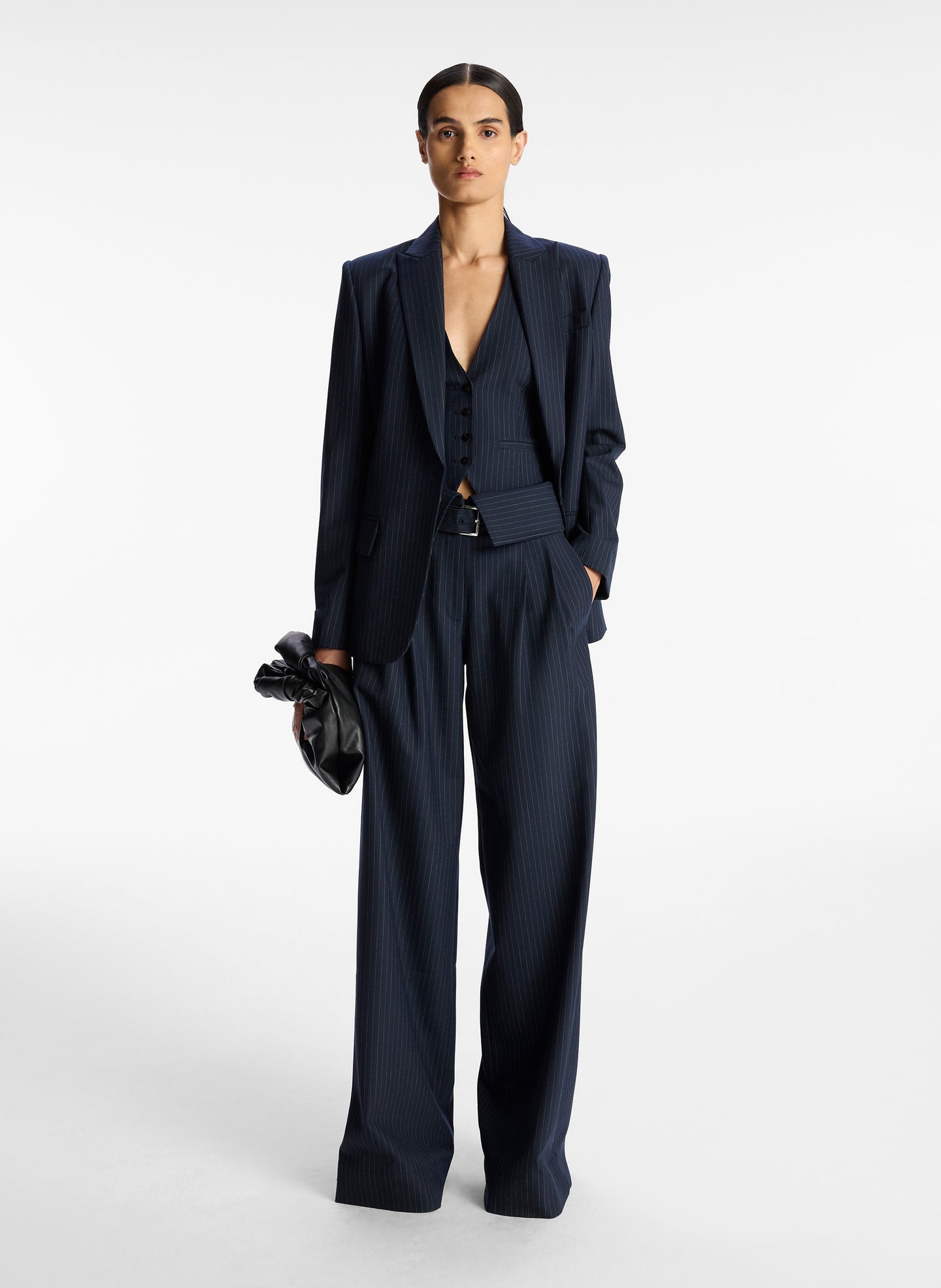 front view of woman wearing navy blue pinstripe suit comprised of blazer, vest, and fold over wide leg pants