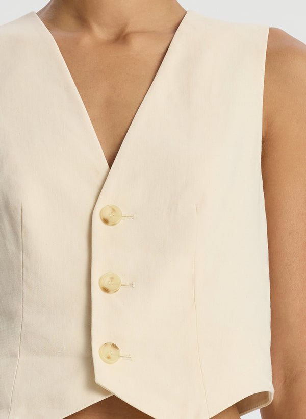 detail view of woman wearing cream vest and matching pants
