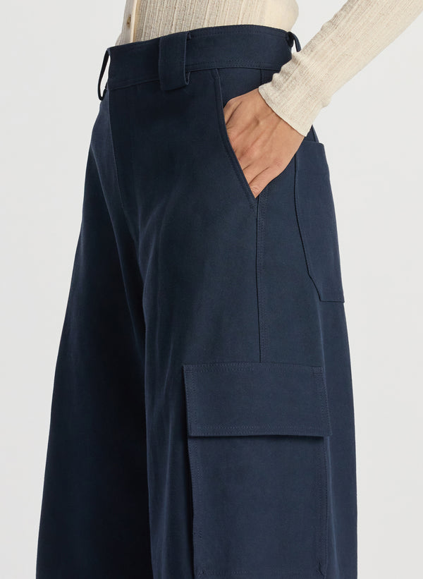 detail view of woman wearing white cardigan and navy blue cargo pants