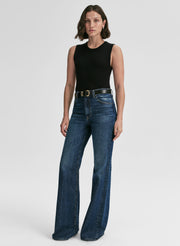 Woman wearing a black sleeveless top and blue jeans on a white background
