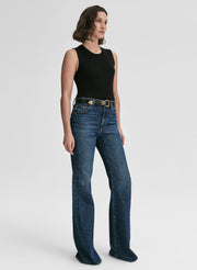 Person wearing a black sleeveless top and blue jeans on a white background