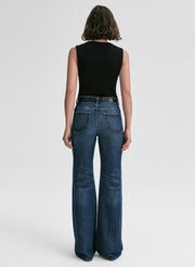 Person wearing blue jeans and a black sleeveless top on a white background